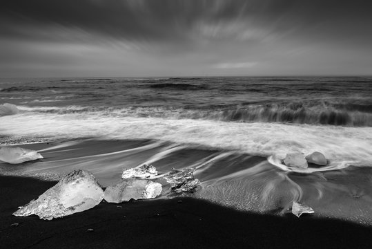 Fototapeta Ice cube with smooth wave at black sand beach Iceland black ans white tone