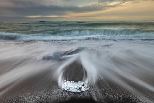 Fototapeta Ice cube with smooth wave at black sand beach Iceland during sunrise
