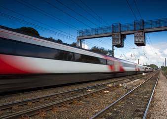 Obraz premium A blurred passenger train speeding past under electric wires.