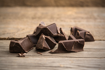 Pieces of chocolate bar on wooden background