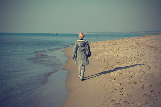 Woman that walks on the seashore in winter