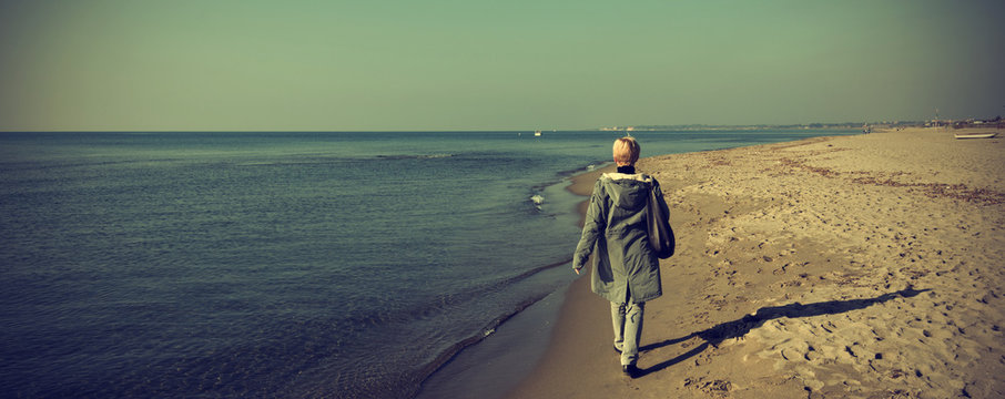 Woman that walks on the seashore in winter