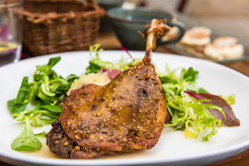 Dish with a roasted duck leg and green salad