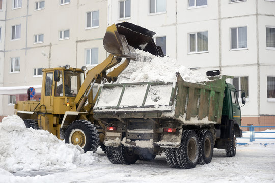 Tractor loads into the car body snow gathered in  yard