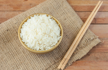 White rice in brown bowl with wood chopsticks