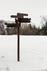 Wooden direction sign covered with snow