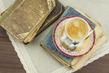 Porcelain cup of coffee and old books. Relax over coffee. Reading old books.
