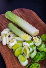 Fresh leeks whole and sliced on a wooden kitchen board