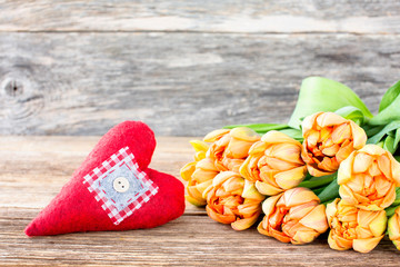Bouquet of tulips and red heart on wooden background. Toned, copy space