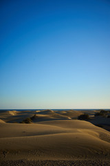 Fototapeta premium Brown Dunes of large beach under blue sky / Large sandy dunes in a wide desert next to southbeach of Gran Canaria