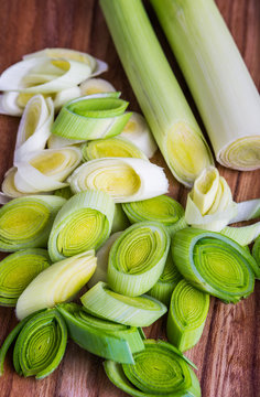 Fresh leeks whole and sliced on a wooden kitchen board