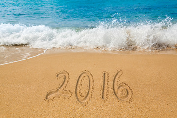 Drawing in sand by ocean of 2016 word