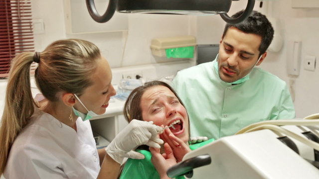 Dentist, assistant and scared patient at surgery office