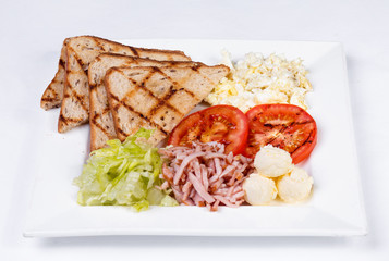 Traditional English breakfast with scrambled eggs, tomatoes, potatoes, toast and fresh salad