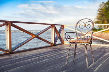 Fototapeta na wymiar Wrought-iron chair standing on wooden terrace