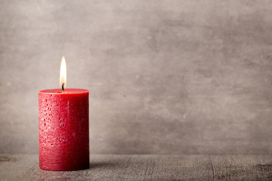 Red burning candle on a gray background. Interior items.
