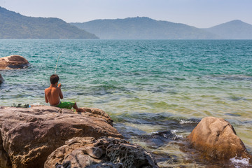 Fototapeta na wymiar Boy fishing on the rock