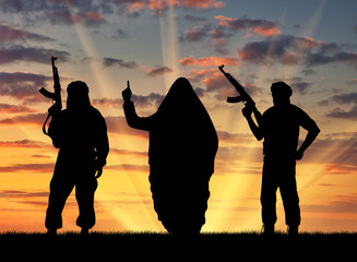 Silhouette of men with rifle standing during sunset