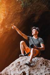 Male photographer on the cliff pointing by his hand