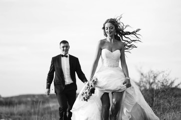 Fototapeta na wymiar Young newly married couple chasing each other in field