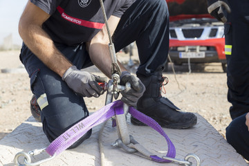 firefighter working with a mechanical tensioning steel cable