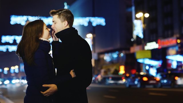 Young couple kissing on the background of the city at night and blurry lights sets