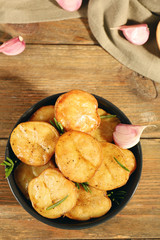 Delicious baked potato with rosemary in bowl on table close up
