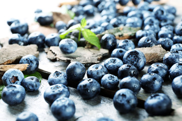 Tasty ripe blueberries with green leaves on wooden table close up