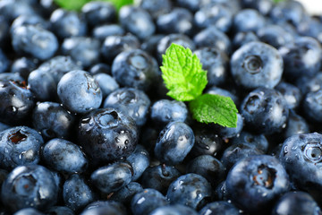 Tasty ripe blueberries with green leaves close up