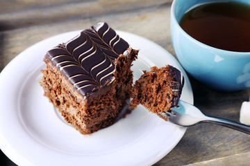 Served table with a cup of tea and chocolate cake on wooden background close-up