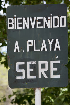 Rusted welcome to beach of Seré sign written in Spanish