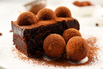 Slice of chocolate cake with a truffle on plate closeup