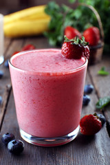 Glasses of fresh cold smoothie with fruit and berries, on wooden background