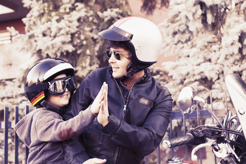 father and son motorcyclists high five