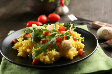 Black plate with vegetable risotto on served wooden table