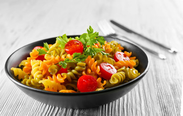Delicious macaroni dish in black bowl on served grey wooden table
