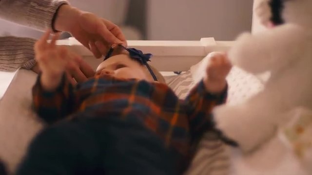 Close up of a mother putting a headband on a baby on a changing table 