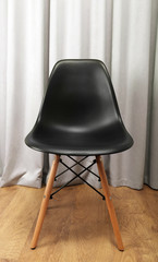 Stylish black chair on grey curtains background
