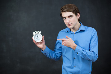 Successful businessman in formal wear pointing at clock