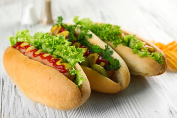 Delicious hot-dogs with chips on white wooden background, close up