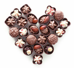 Heart shape composition of chocolate candies on white background