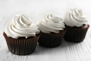 Tasty cupcakes on white wooden background, close up