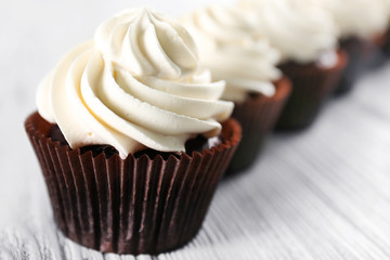 Tasty cupcakes on white wooden background, close up