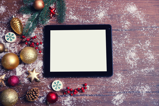 Tablet and Christmas decor on wooden background