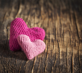 Fototapeta premium Two crochet pink hearts on wooden background