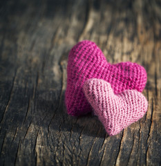Two crochet pink hearts on wooden background