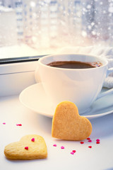 Winter snow-covered window, a cup of coffee and biscuits valenti