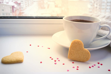 Cup of coffee and cookies valentines on background of a winter w