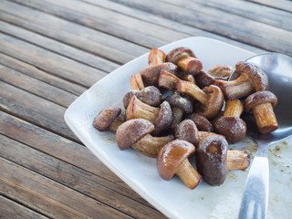 shitake mushroom fried with sauce and salt on wooden table