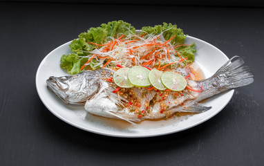 Fish dish - Steamed snapper with lemon on black background. Top